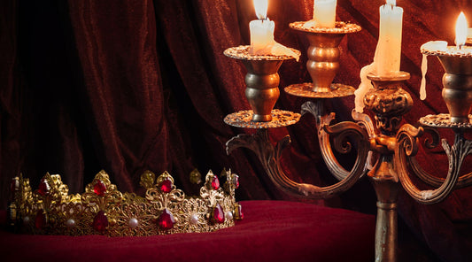 a gemstone gold crown on a cushion with a candelabra to the right