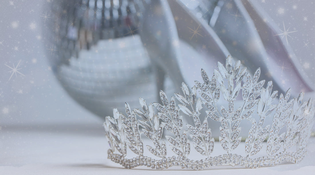 a rhinestone tiara in foreground. Silver high heels and disco ball in the background with snowflakes
