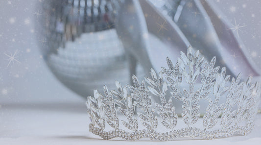 a rhinestone tiara in foreground. Silver high heels and disco ball in the background with snowflakes