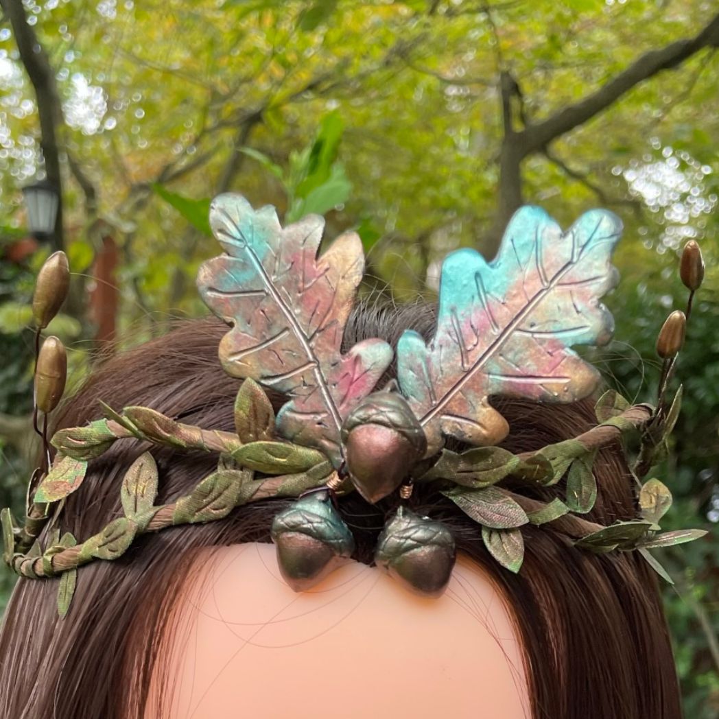 3 Acorns and 2 oak leaf crown in muted Fall colors with green and gold leaf vines and golden buds to the sides.  The crown displayed on a model.