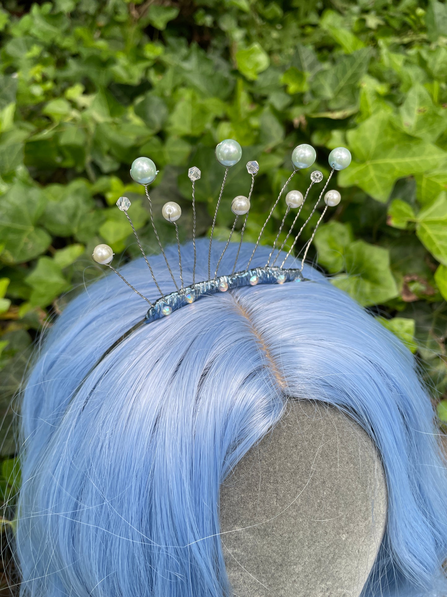 Right profile of Blue celestial tiara crown on a model with blue hair in forest setting.