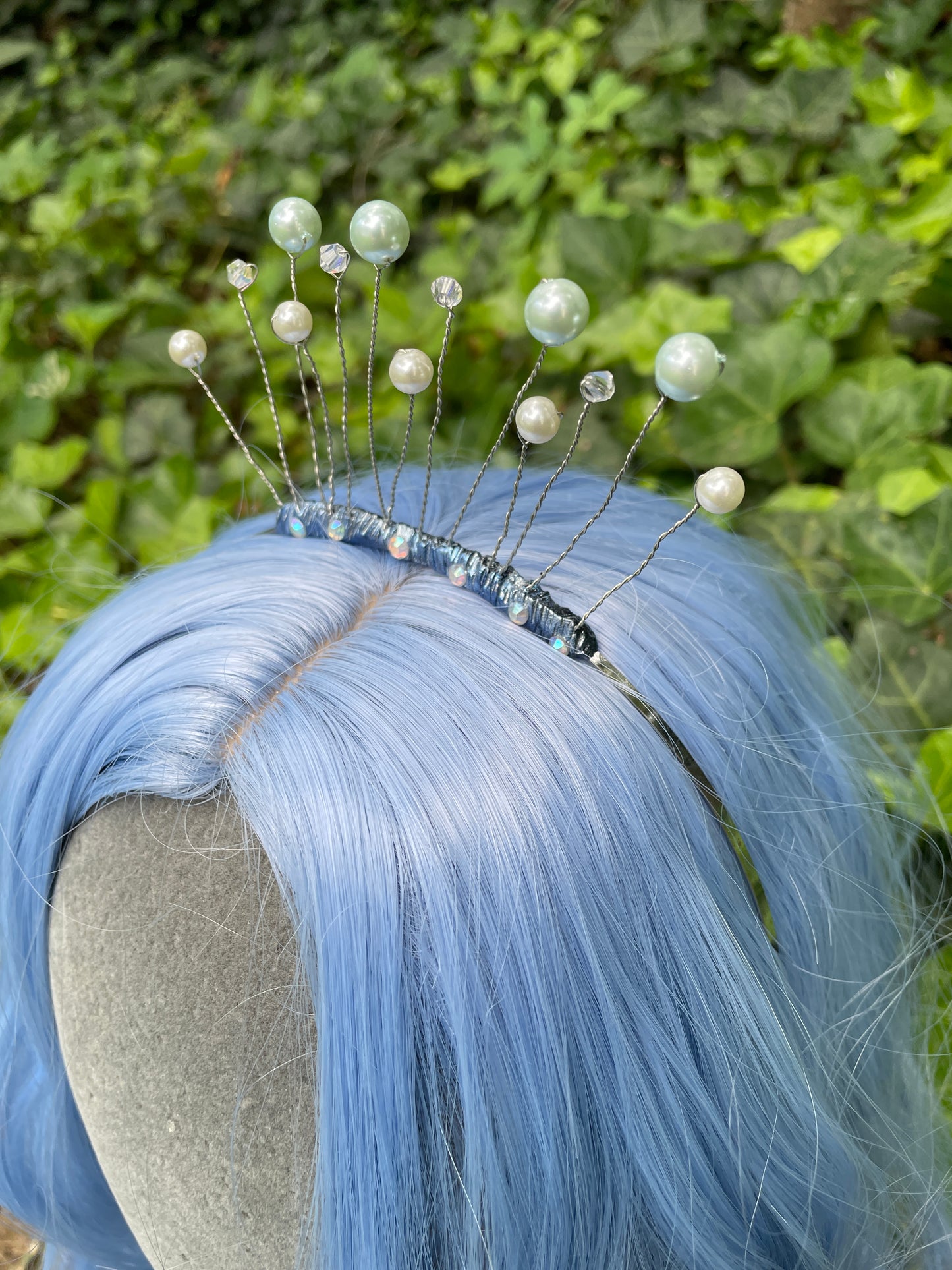 left profile of Blue celestial tiara crown on a model with blue hair in forest setting.