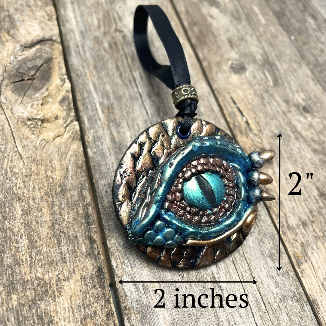 A round dragon eye ornament with metallic green gold and bronze coloring with black satin ribbon