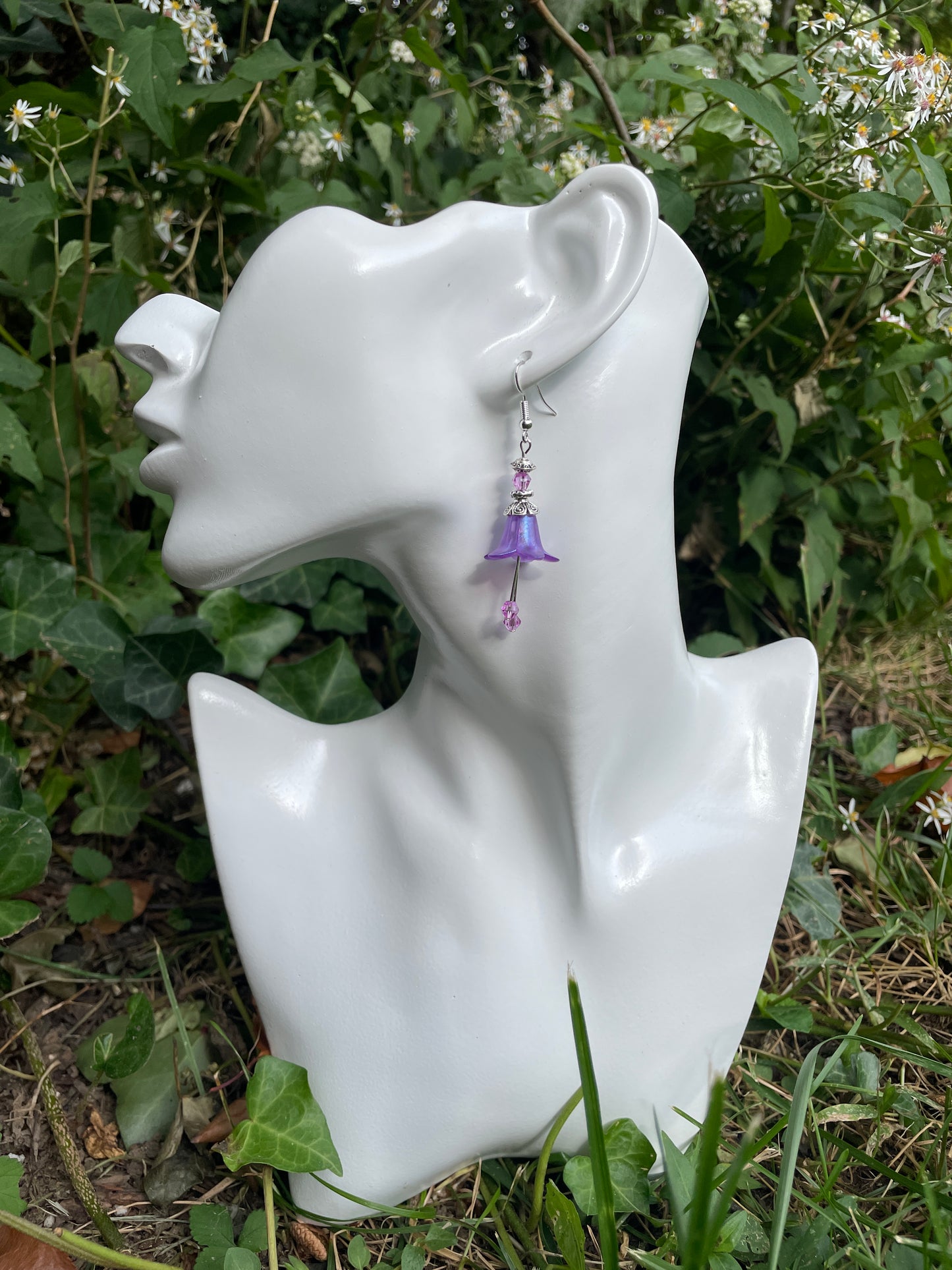 Purple bellflower earrings with silver accents and purple crystals on model.