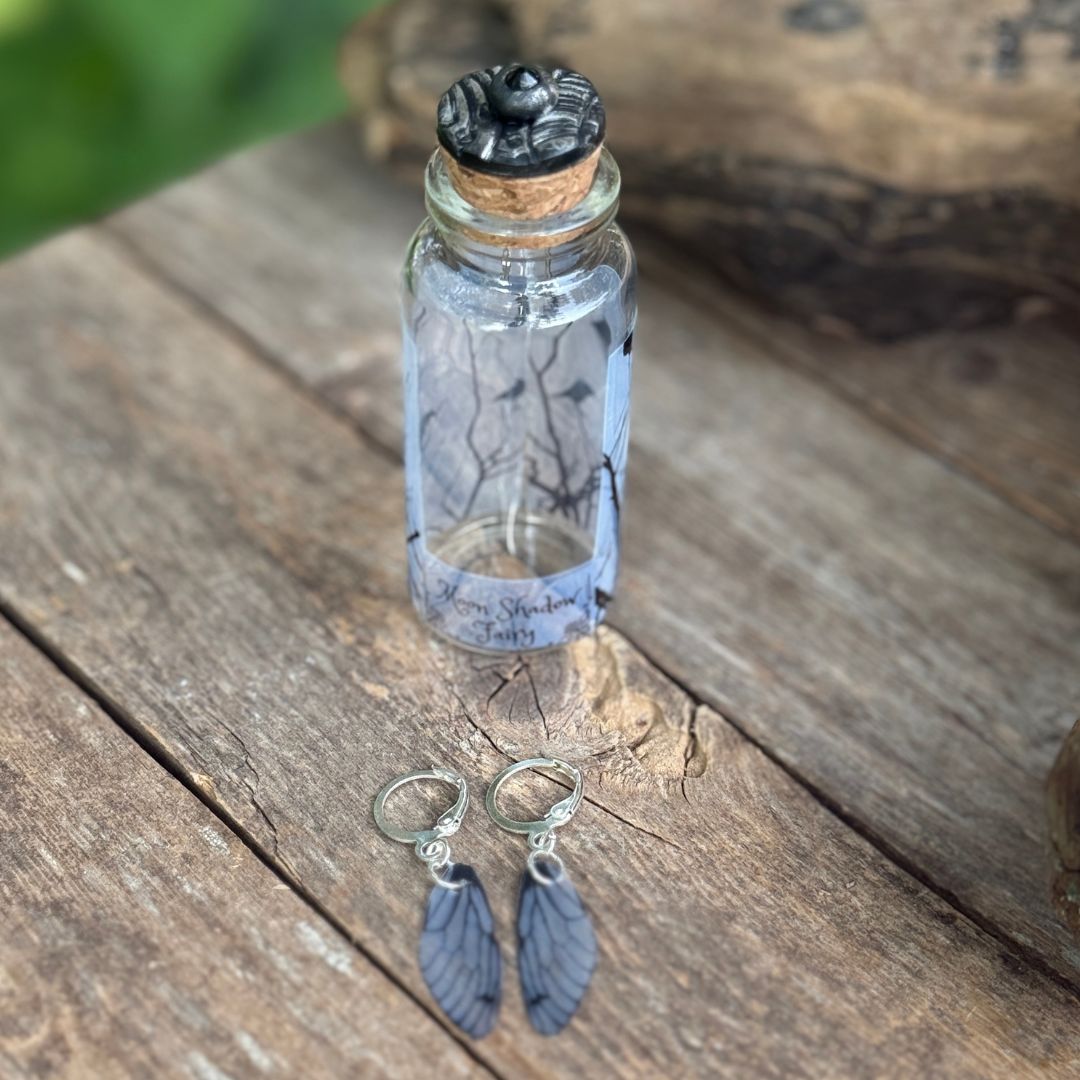 Silver earrings next to a small glass bottle.