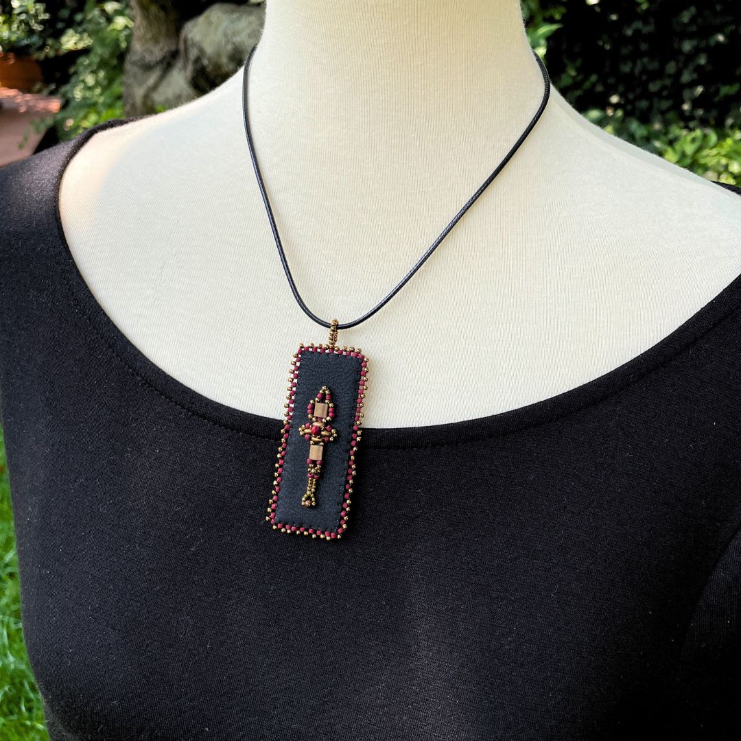 red and gold Renaissance beaded faux leather rectangle pendant with beaded edge on a model.
