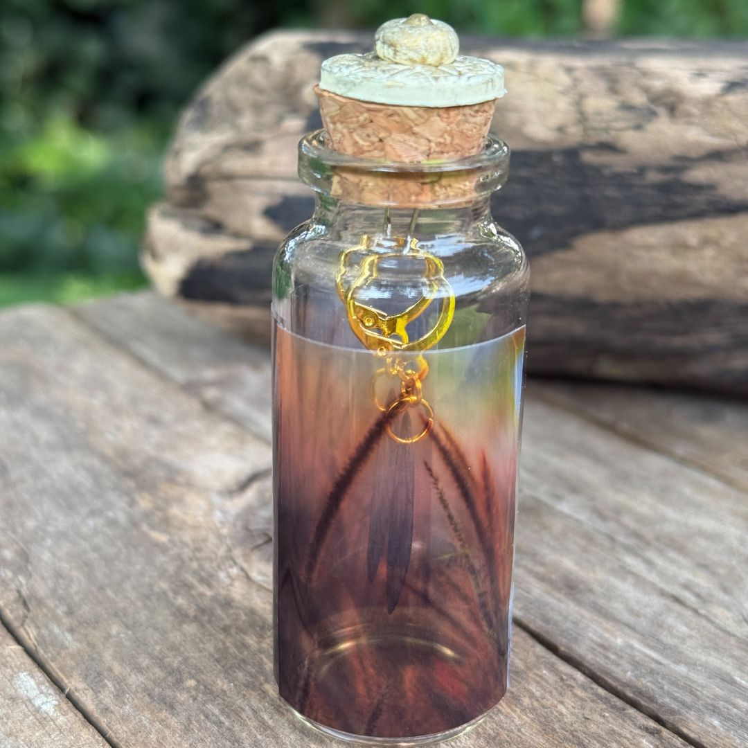 Glass bottle with cork lid containing a pair of fairy earrings on a wooden surface