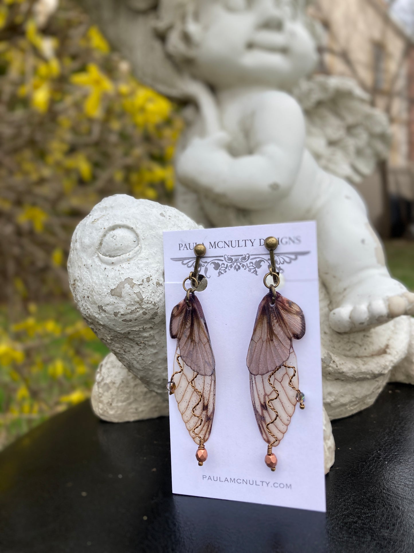 Fairy wing earrings with copper wired crystals with bronze clip on components on an earring card in garden