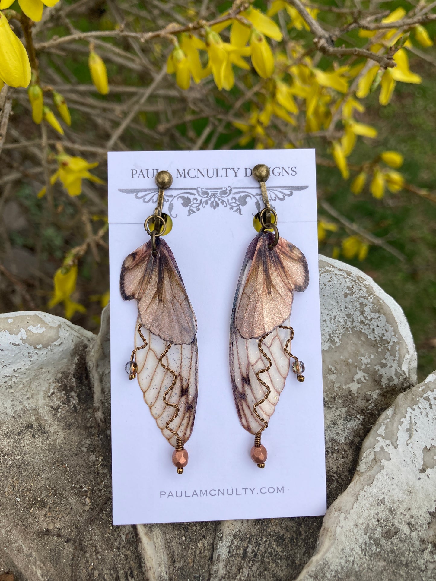Fairy wing earrings with copper wired crystals with bronze clip on components on an earring card in garden