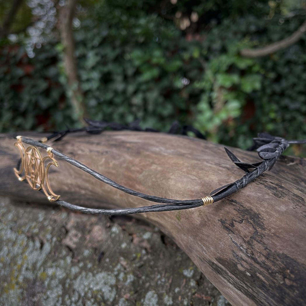 Side profile of triple moon black wired crown sitting on a tree branch