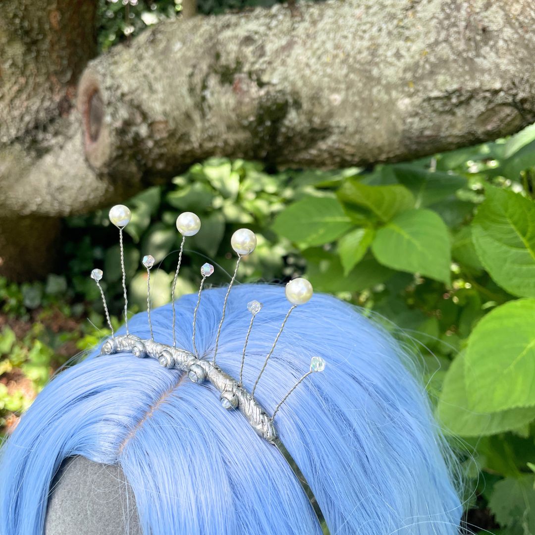 Closeup of celestial tiara on model with blue wig in a garden setting