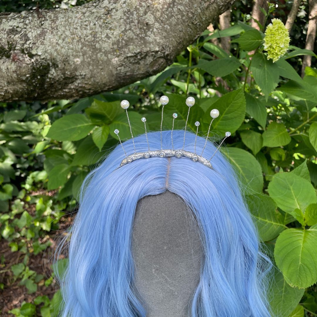 Closeup of celestial tiara on model with blue wig in a garden setting