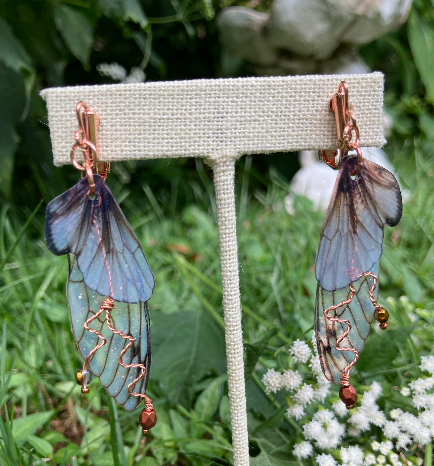 Fairy wing earrings with copper wired crystals with clip on components on an earring stand in garden