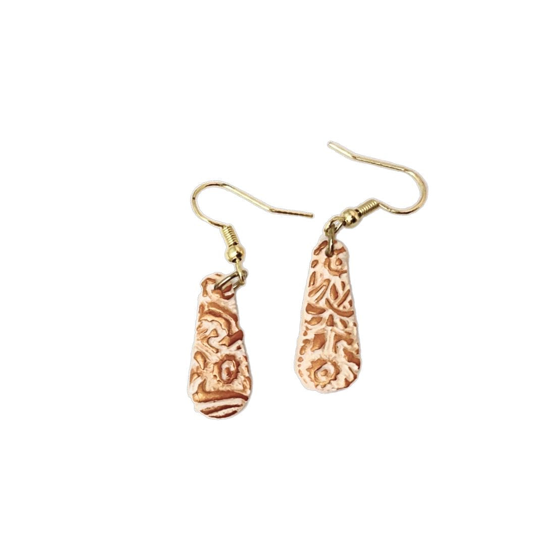Beige teardrop earrings with copper highlights on a white background