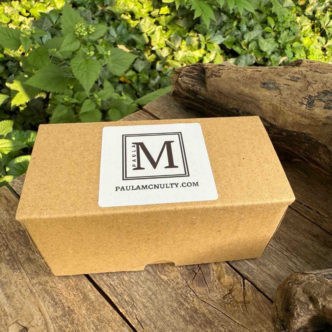 Brown cardboard box with a label on a wooden surface with greenery in the background