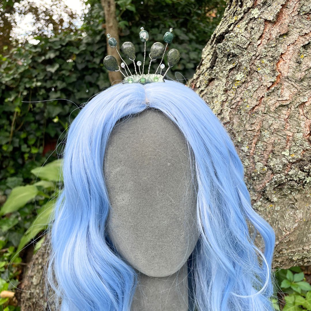 green gemstone headband tiara on model with a blue wig in a forest setting.
