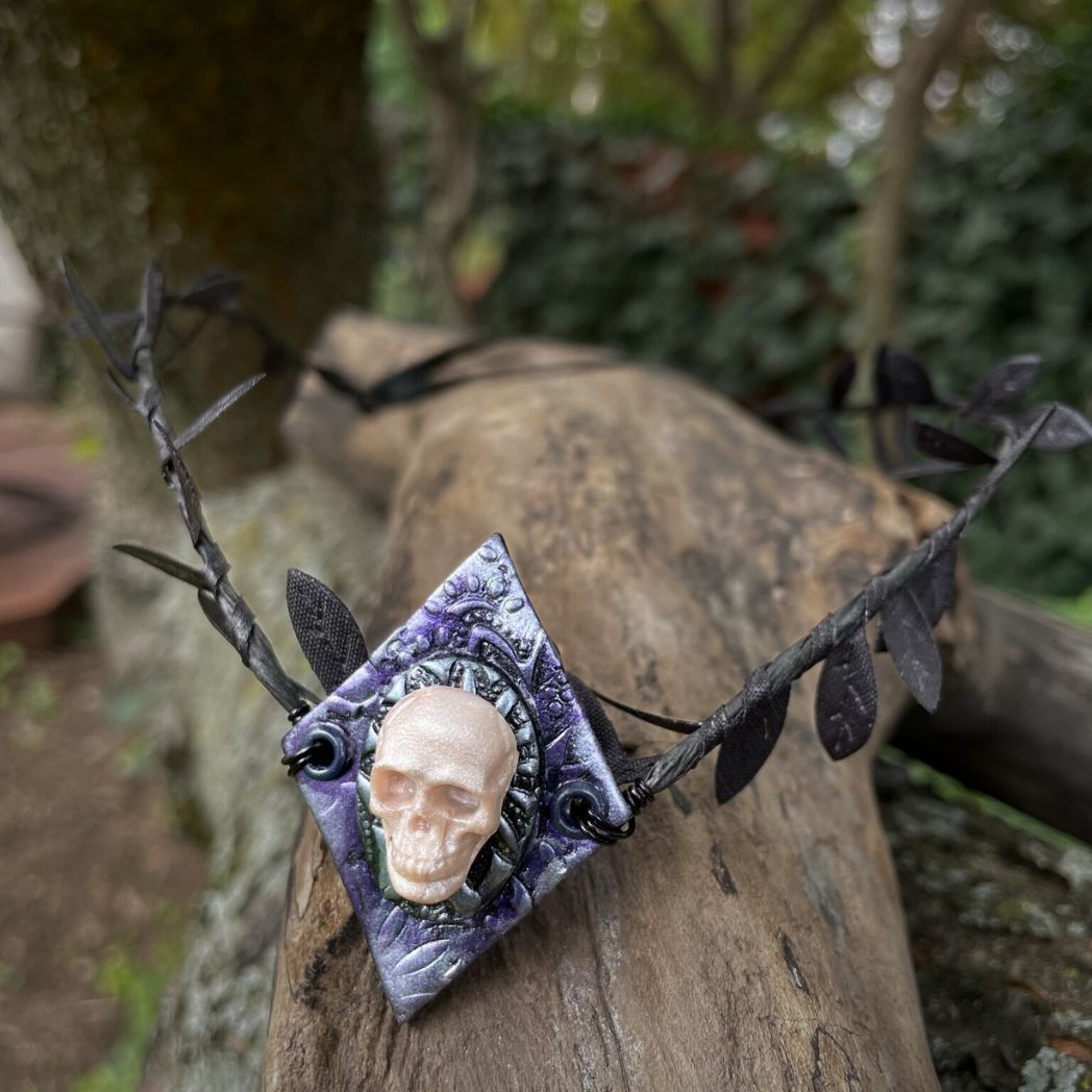 Skull black leaf wire crown resting on a tree branch.