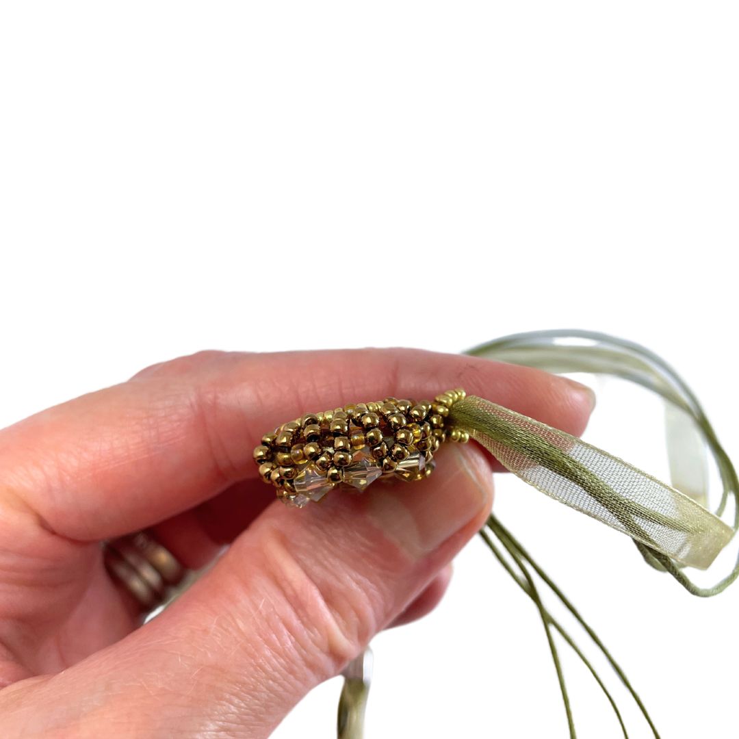Side view of yellow beaded crystal neckclace held in a hand against a white background.