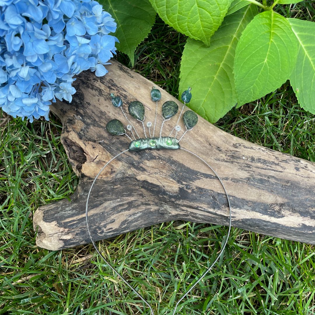 forest nymph headband tiara laying on a log next to a blue flower.
