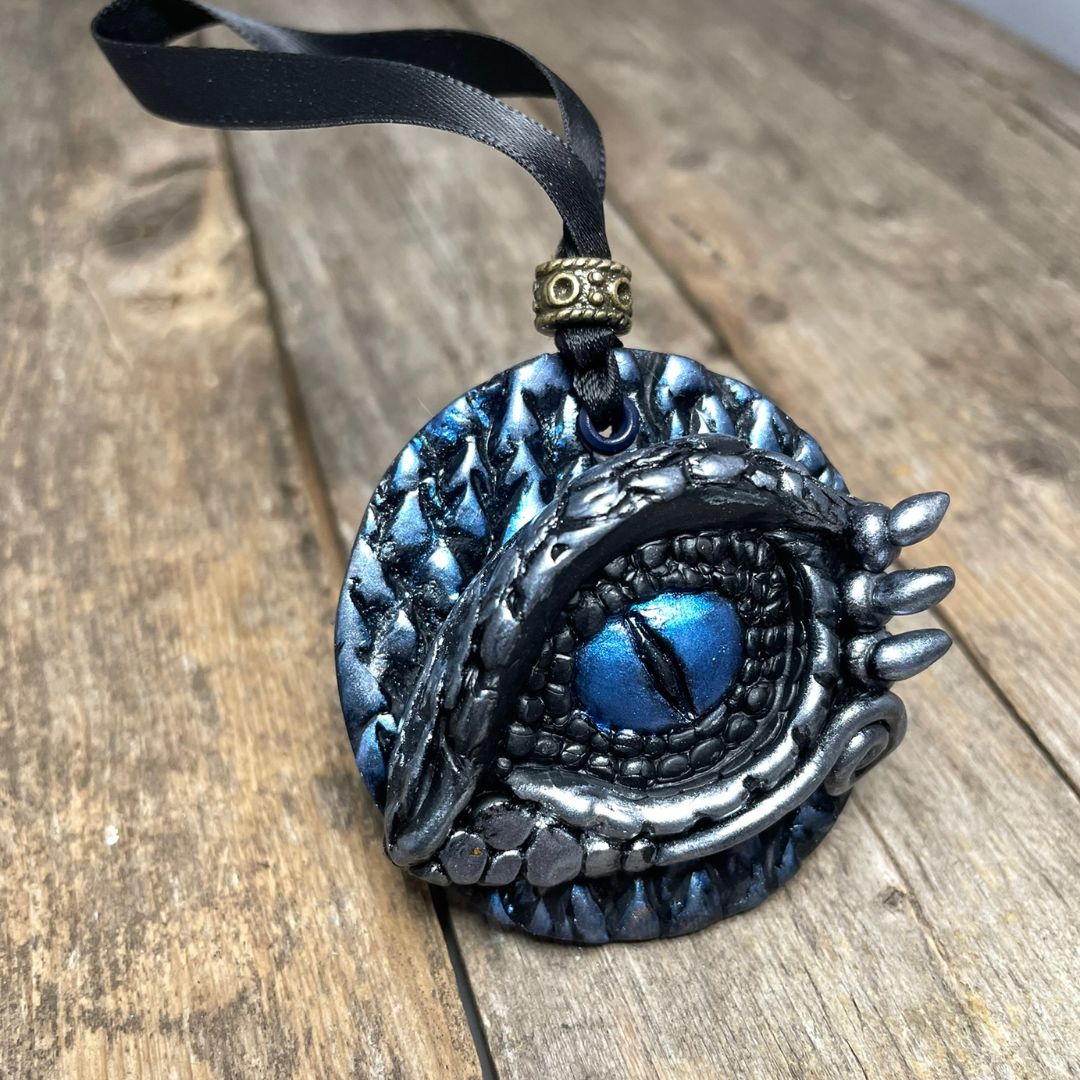 A round dragon eye ornament with metallic silver and blue coloring with black satin ribbon