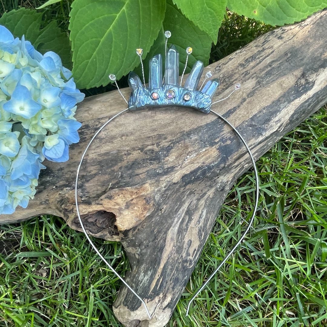 Blue tiara headband resting on a log with a Hydrangea flower in a garden