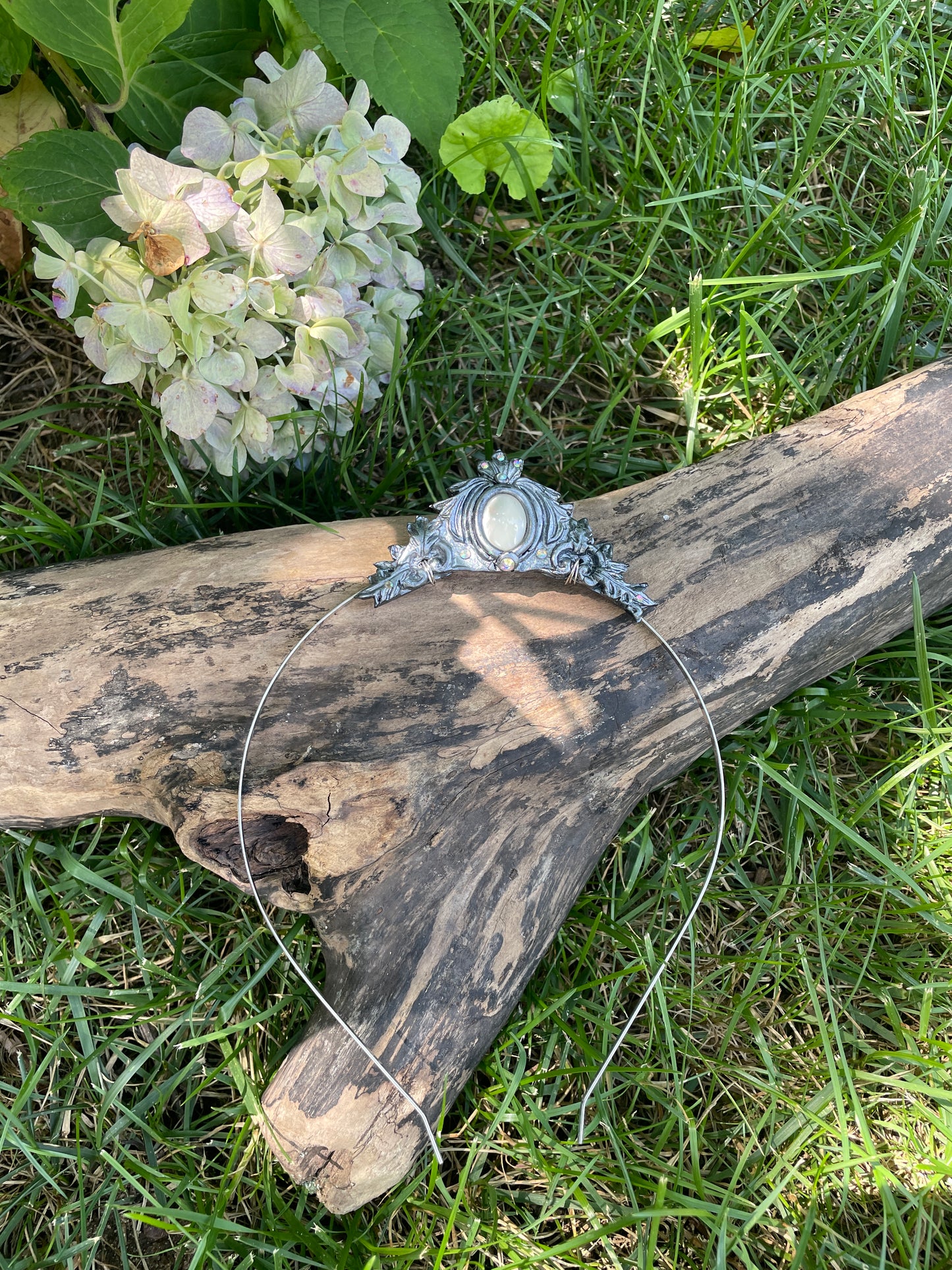 Silver mother of pearl mermaid crown on a a tree branch in the garden