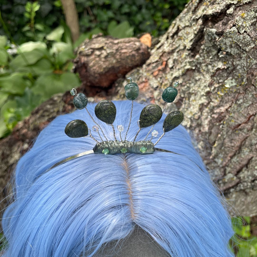 Top view of moss green headband tiara on model with a blue wig in a forest setting.