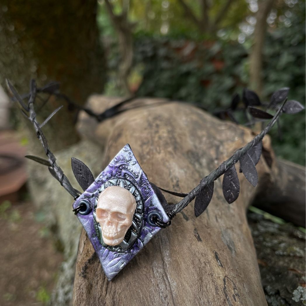 Skull black leaf wire crown resting on a tree branch.