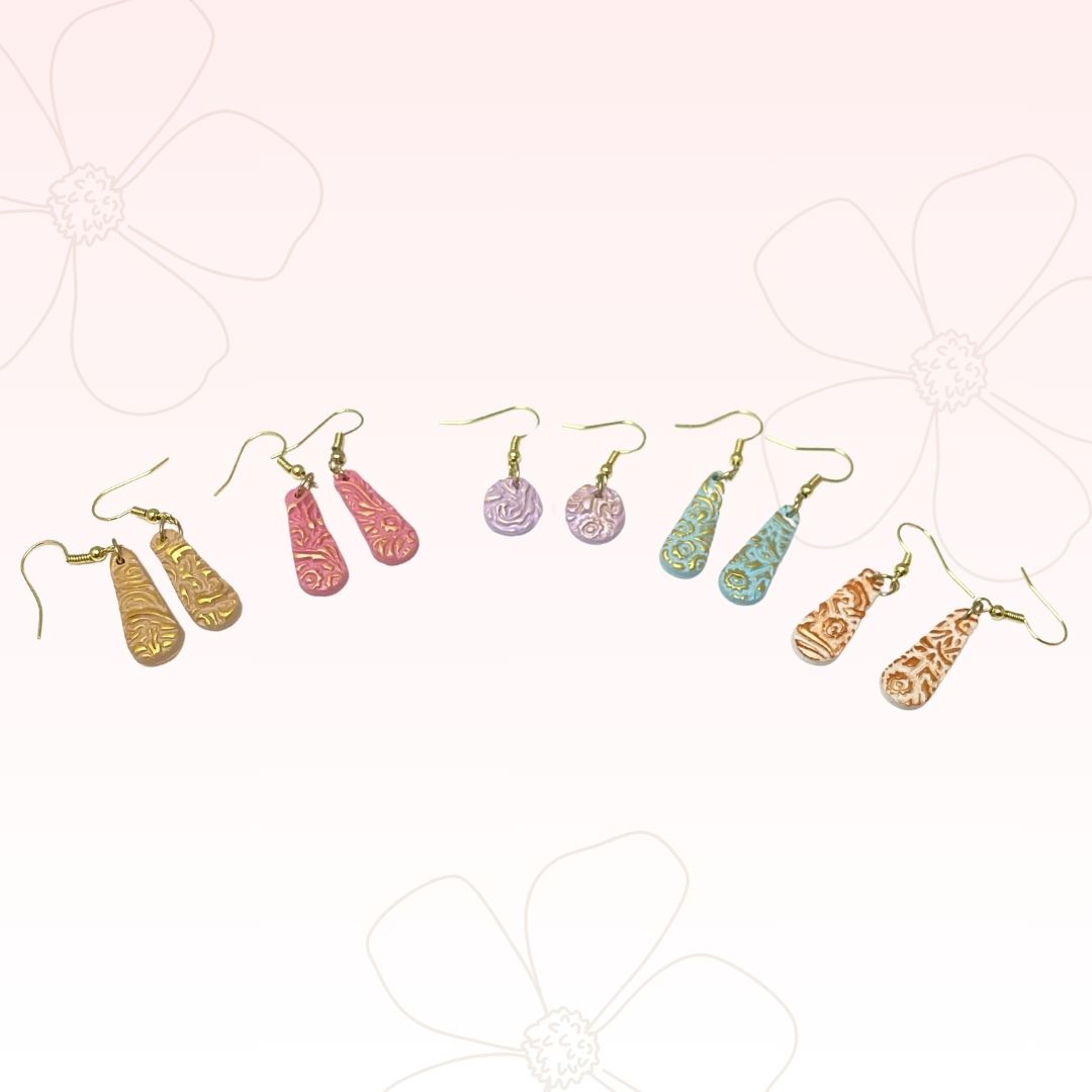 pastel colored teardrop earrings on a pale pink background with large flowers