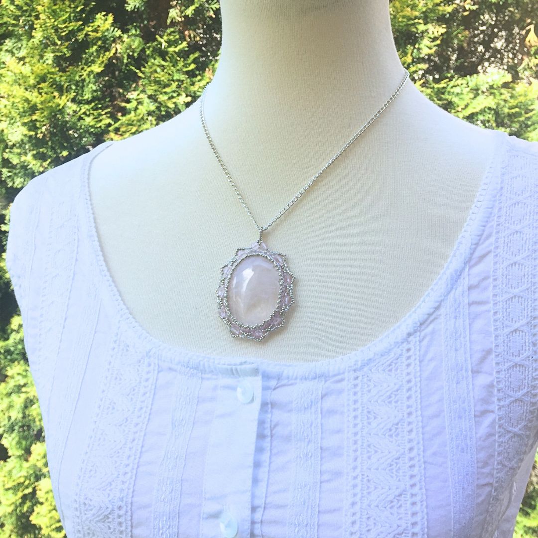 Rose quartz pendant on a model in a garden setting.