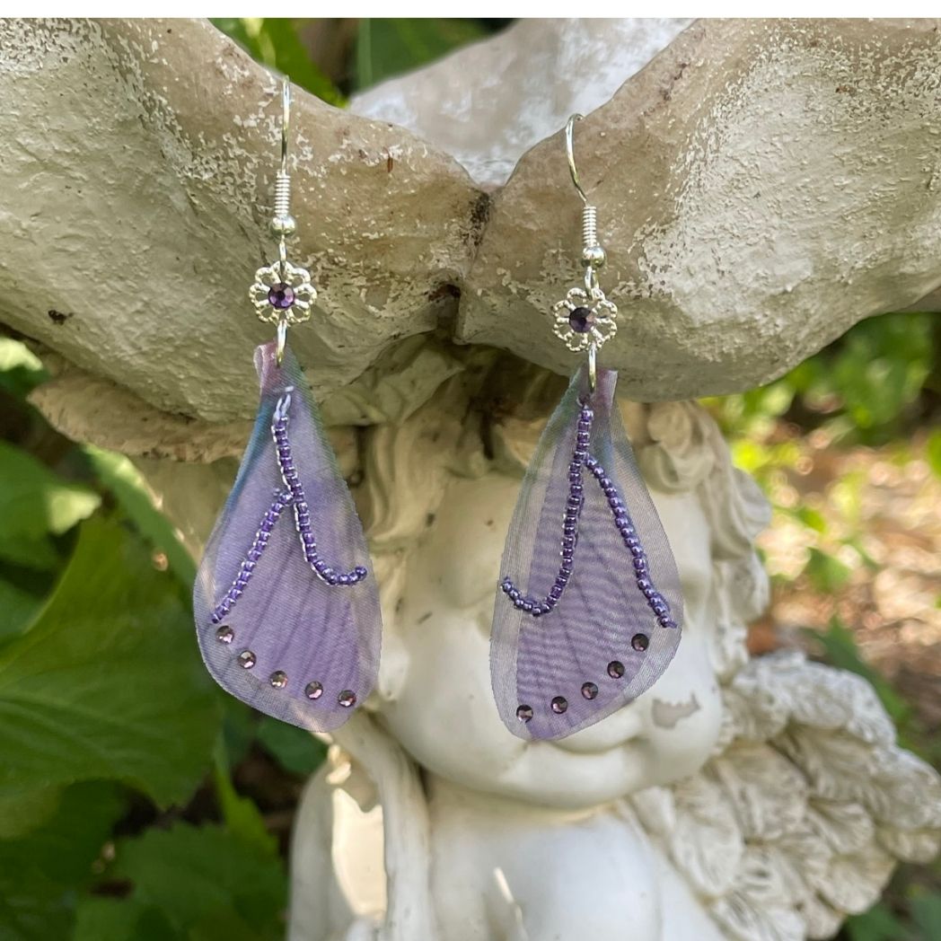 purple beaded fabric wing earrings with purple crystals and a flower bead with purple crystal above wings connecting to the ear wires