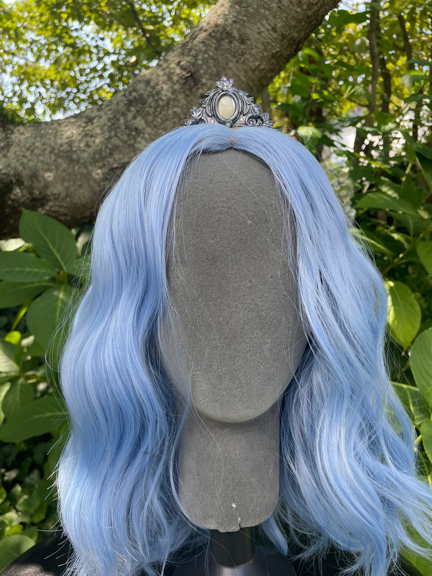 Silver mother of pearl mermaid crown on a model with blue hair in a garden