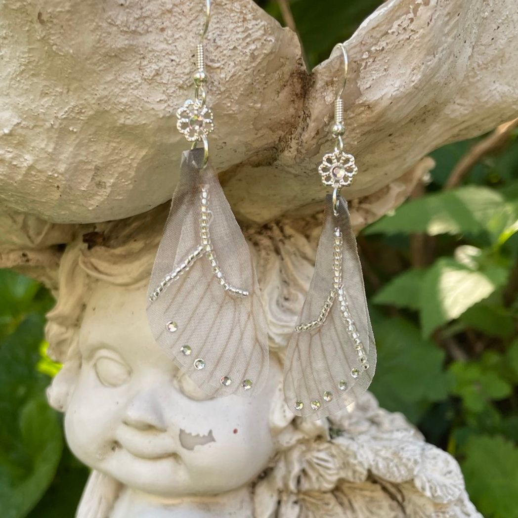 Silver beaded gray sheer fabric butterfly wing earrings with crystals and a flower bead connecting to the ear wires.