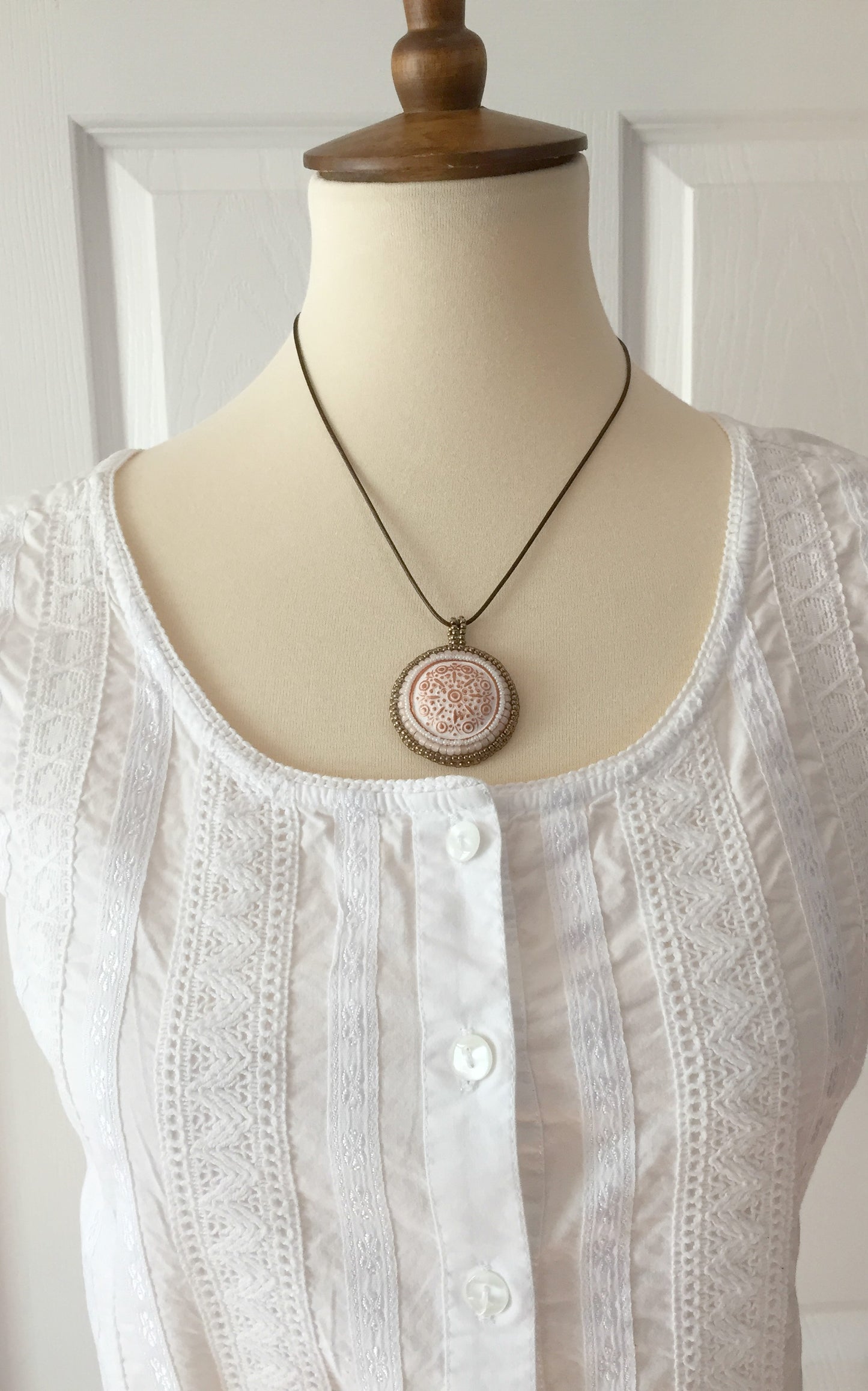 copper and white beaded medallion necklace on model wearing white top