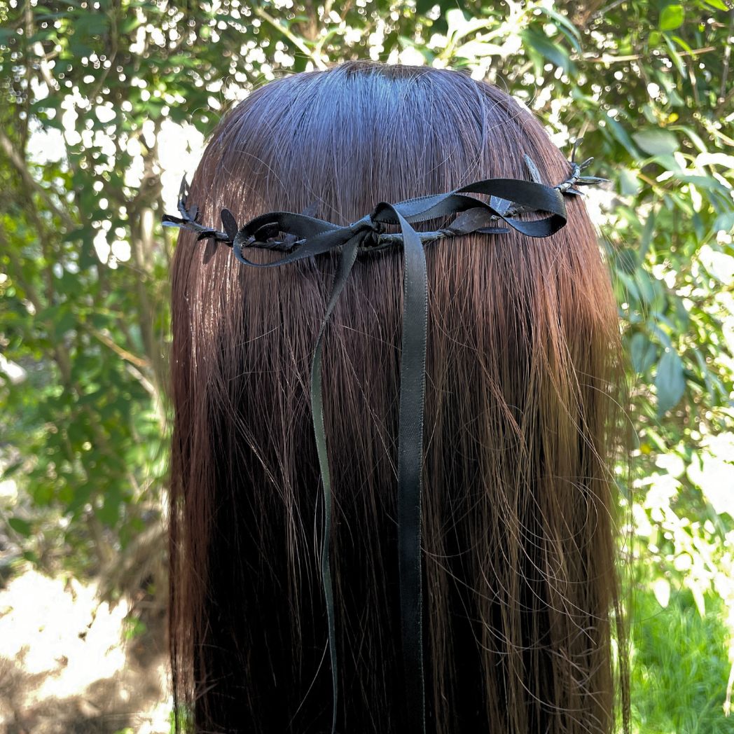 Back of raven skull circlet showing the black satin ribbon tied at the back of the head on a model.