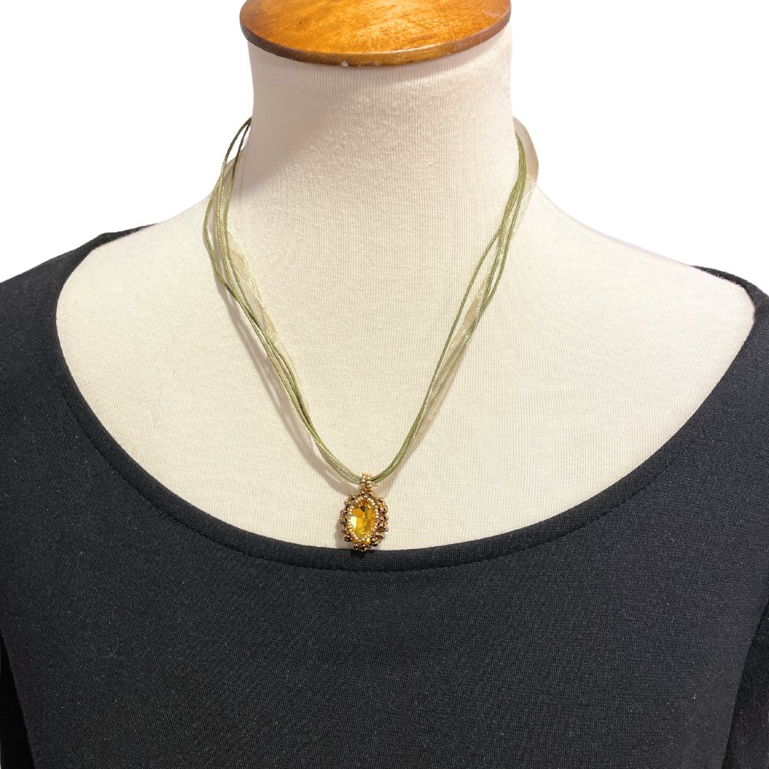 Model wearing yellow beaded crystal necklace with organza ribbon cord against a white background.