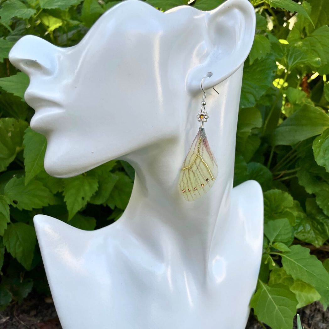 Yellow sheer fabric beaded butterfly wing earrings with peach color crystals and a flower bead connect the wings to the ear wires on a model