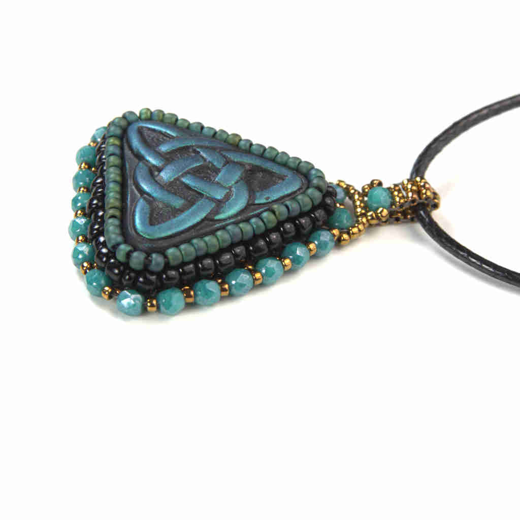 Side view of blue celtic trinity knot pendant with turquoise and gold bezel and bail