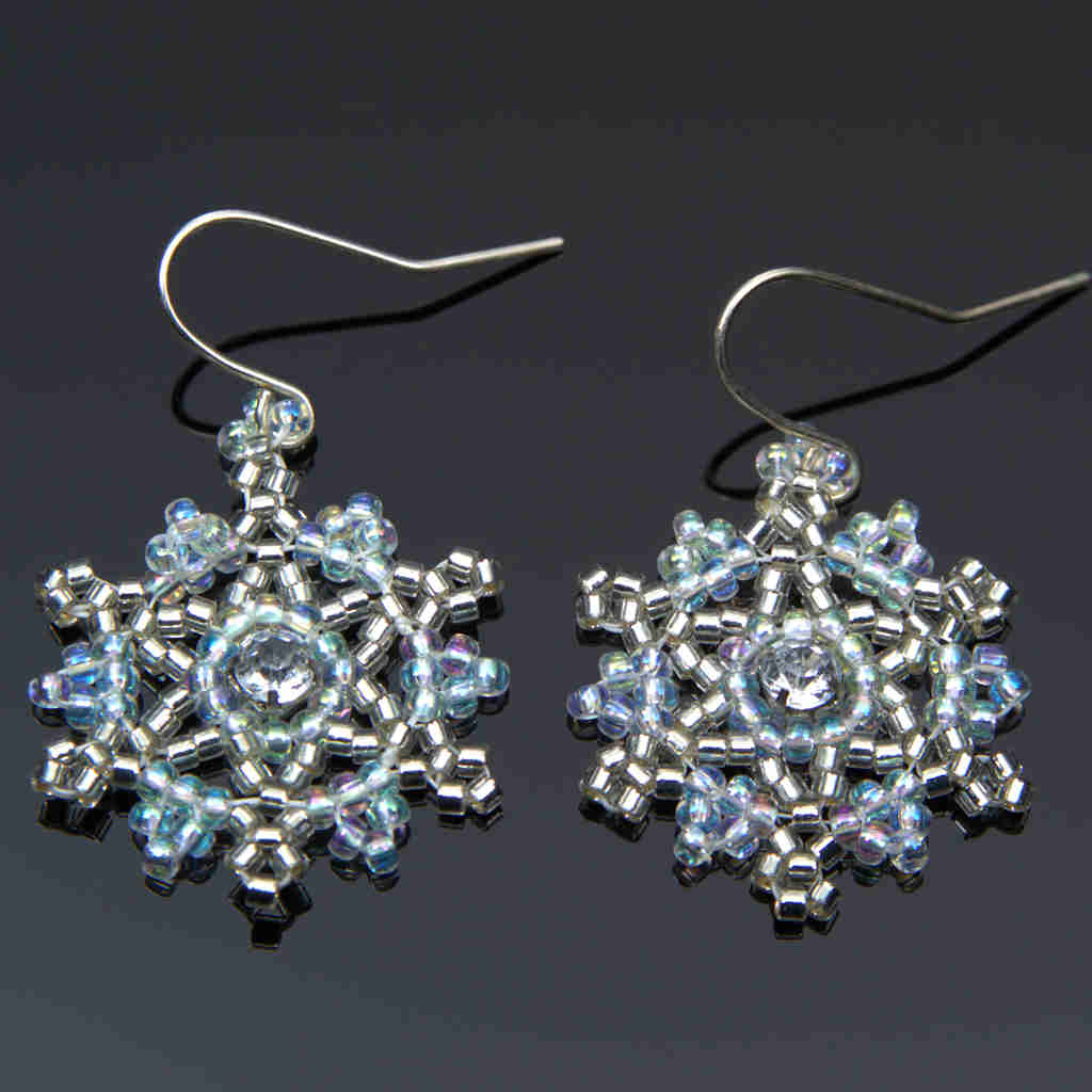 large seed beaded snowflake earrings in blue and silver on a gray background