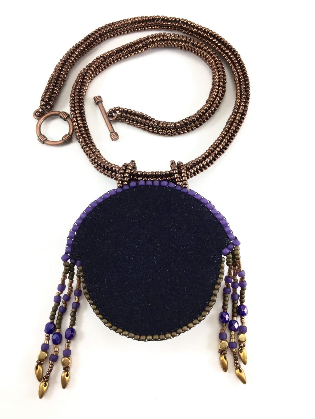 Back of sun goddess statement beaded gold art necklace showing black faux suede finish and toggle necklace clasp