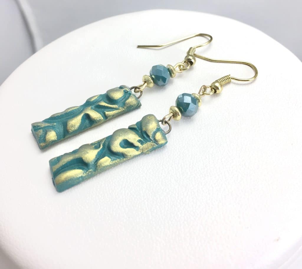 Side view of teal & gold bar earrings with green crystals and gold accents.