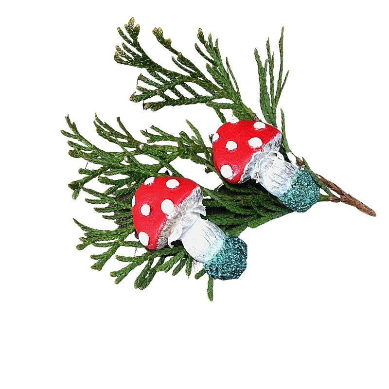 Red mushroom vocal alligator hair clips laying on a piece of fir greenery.