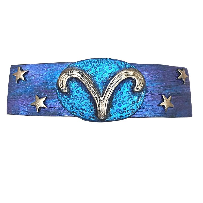 Blue and purple hair clip with a gold Aries symbol in the center with 2 gold stars on each side.
