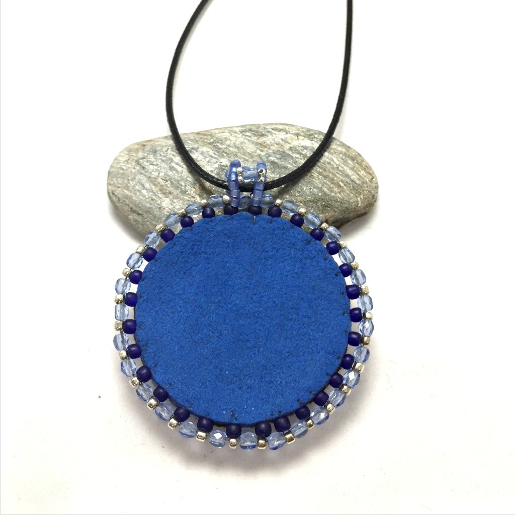 Back of round blue sodalite gemstone necklace with blue faux suede.