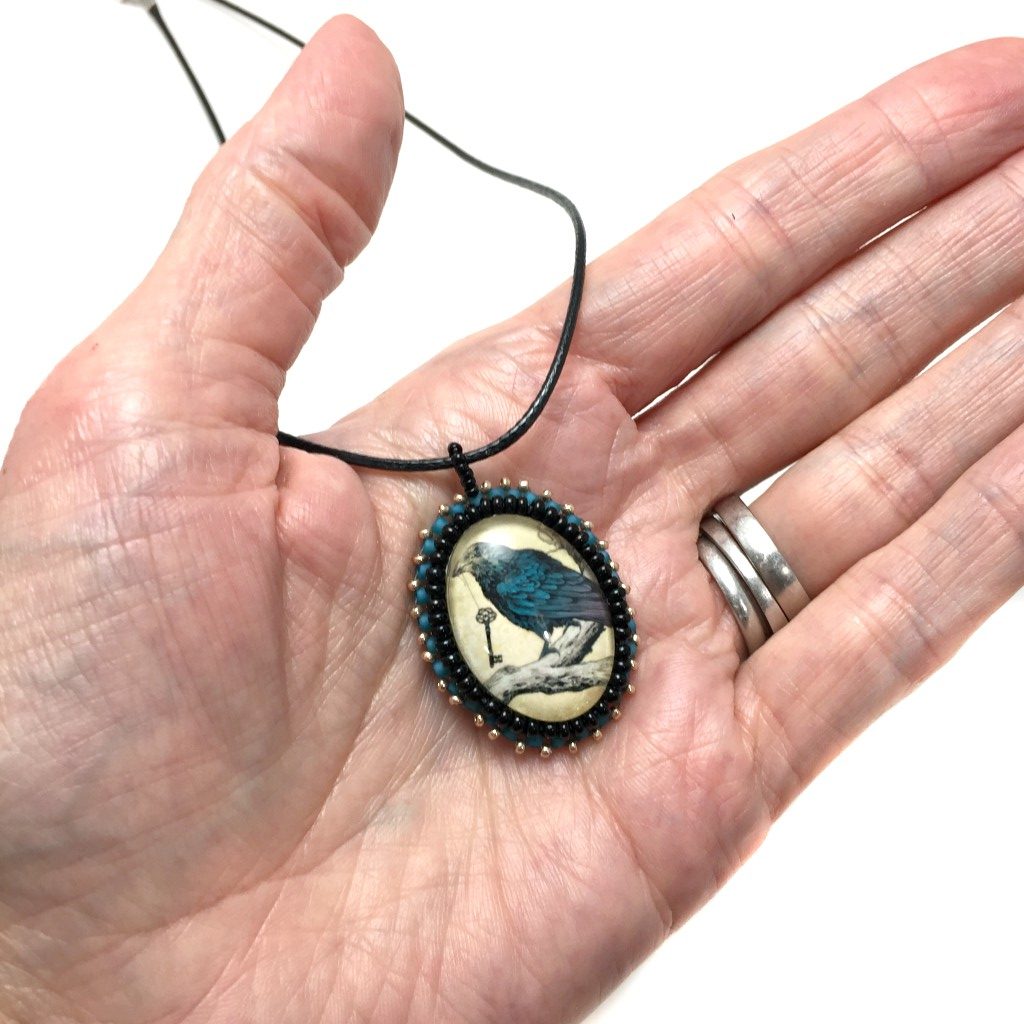 blue raven pendant in hand