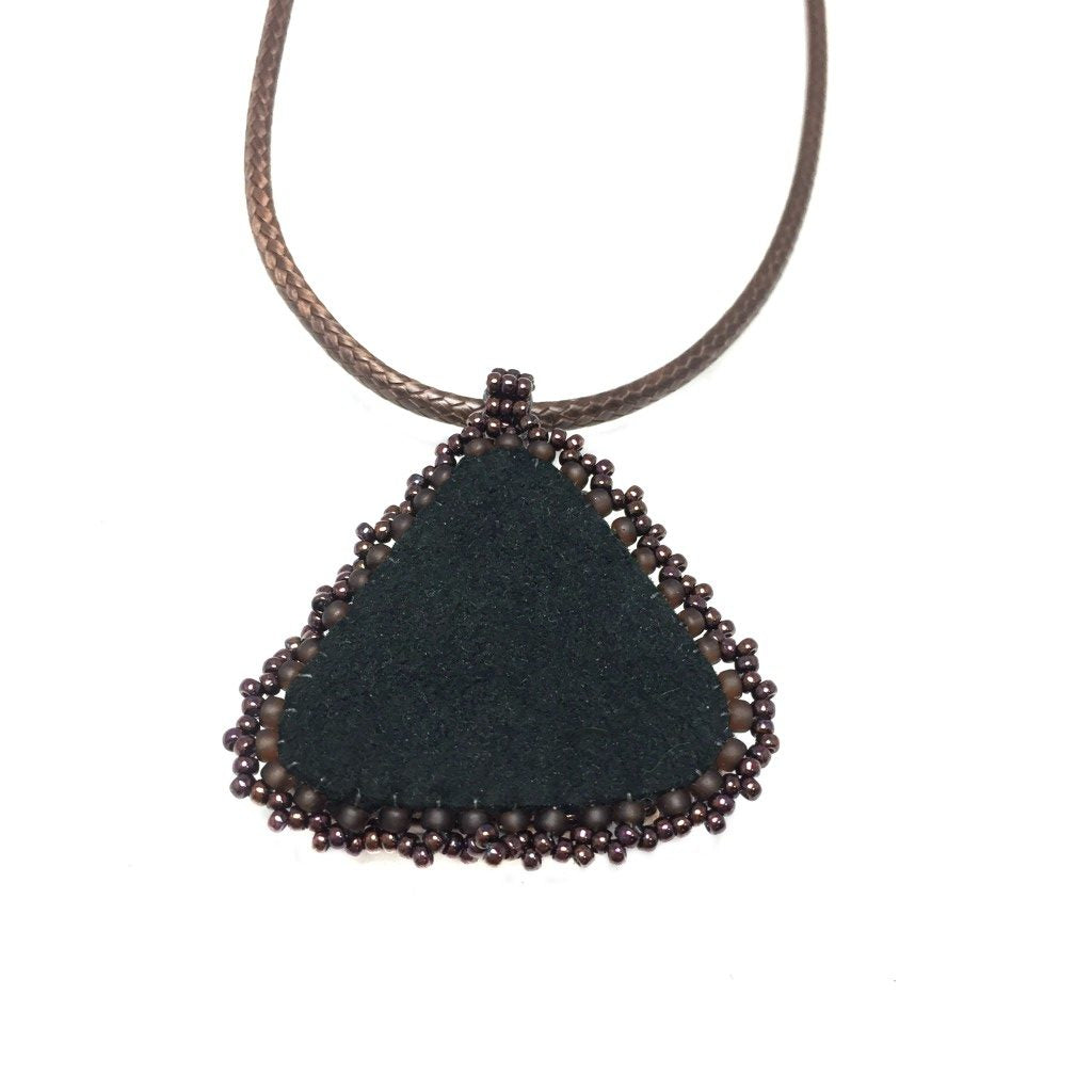 Back of Bronze celtic trinity knot necklace with bronze seeded edging on a brown cord necklace showing black faux suede and bronze beaded edging.