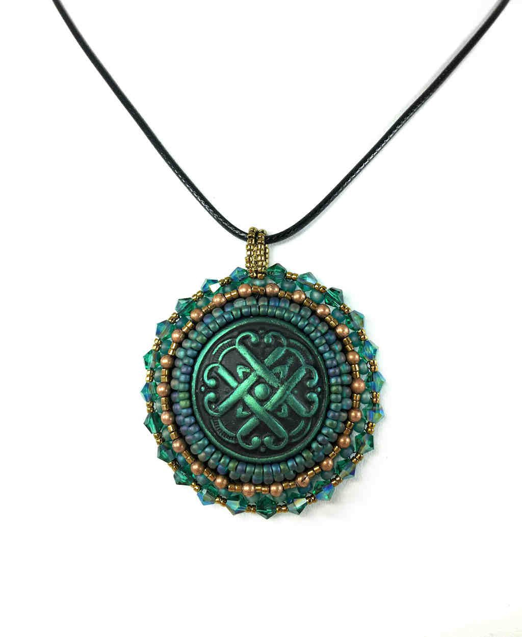 A green Celtic love knot motif, surrounded by green and gold seed bead edging  and green  crystals. Pendant is on a black cord chain.
