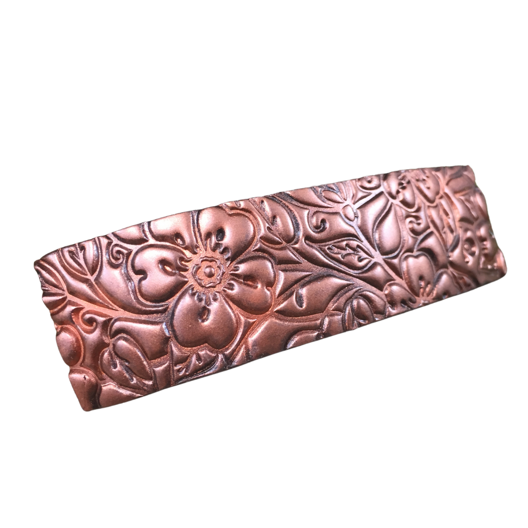 Close-up view of metallic copper colored, textured flower hair barrette.