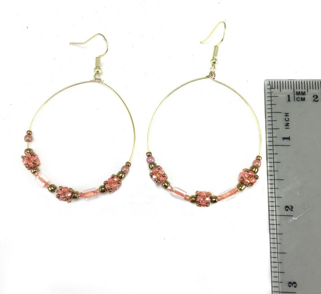 2 inch gold wire hoop earrings with coral color cube beads, crystals, and gold seed beads. A ruler next to the earrings showing size reference.