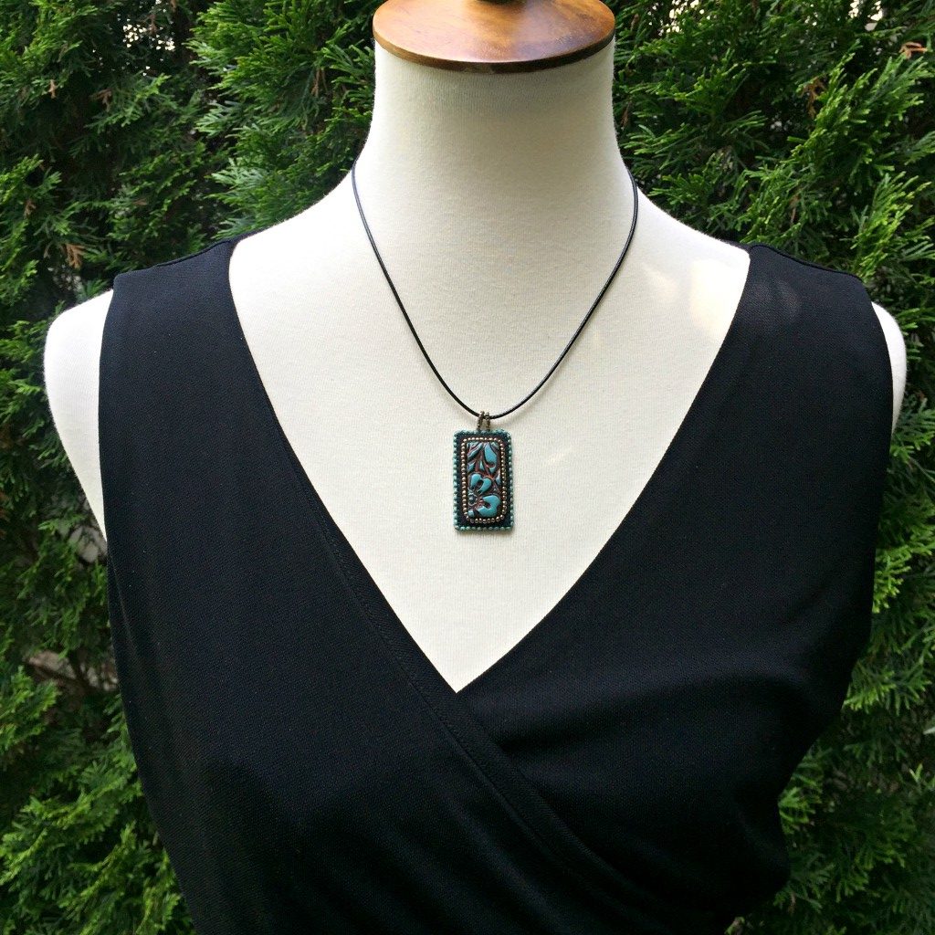 Model wearing patina faux leather floral textured rectangle pendant necklace.